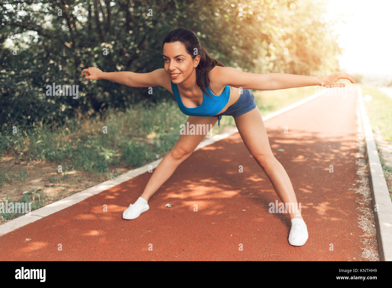 Young urban runner donna facendo esercizio di stretching dopo fare jogging a tartan via. Foto Stock