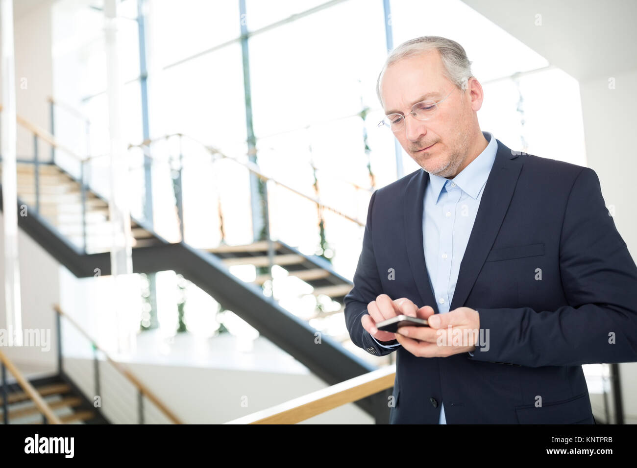 Fiducioso imprenditore senior texting sullo smartphone in office Foto Stock