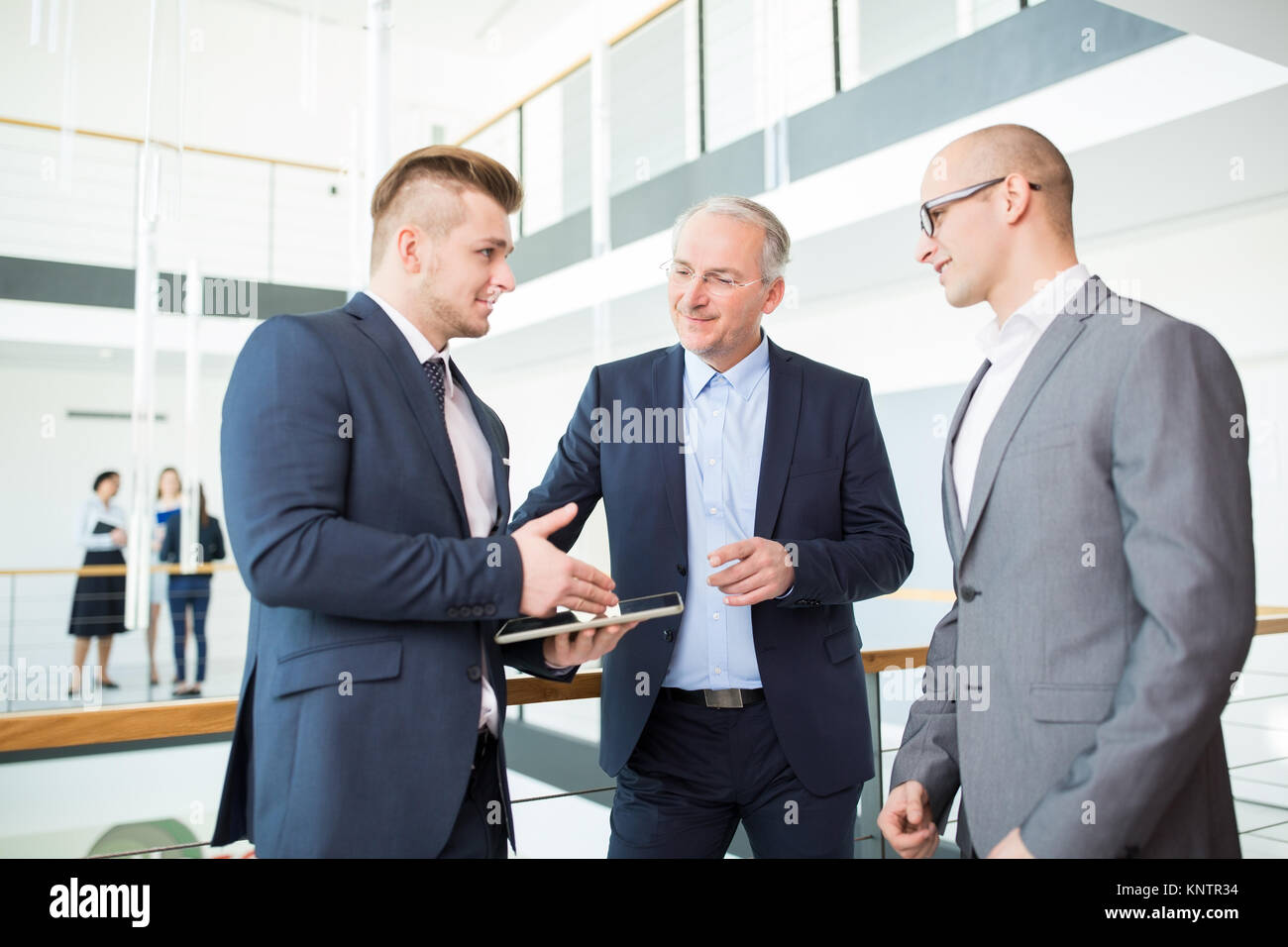 Maschio professionale progetto spiegare ai colleghi sulla tavoletta digitale in ufficio Foto Stock