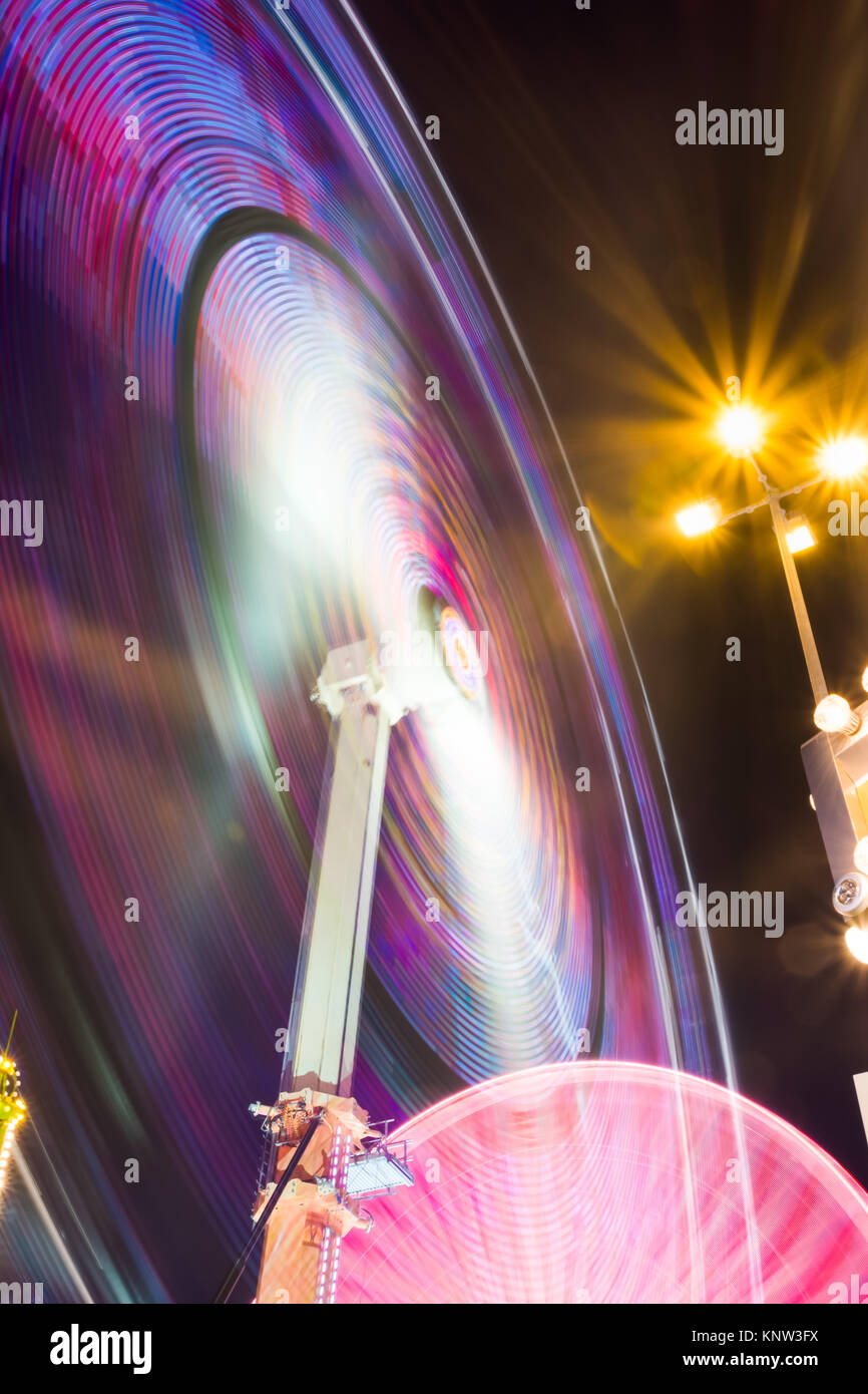 Rotazione della ruota Ride Rollercoaster luci al neon con esposizione lunga notte colorato Foto Stock