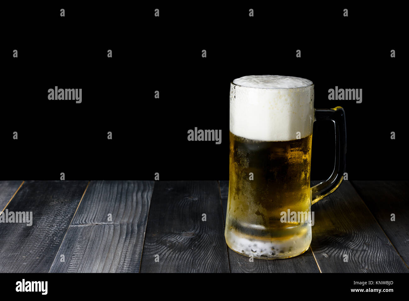 Birra di vetro su di un tavolo di legno e sfondo nero con spazio di copia Foto Stock