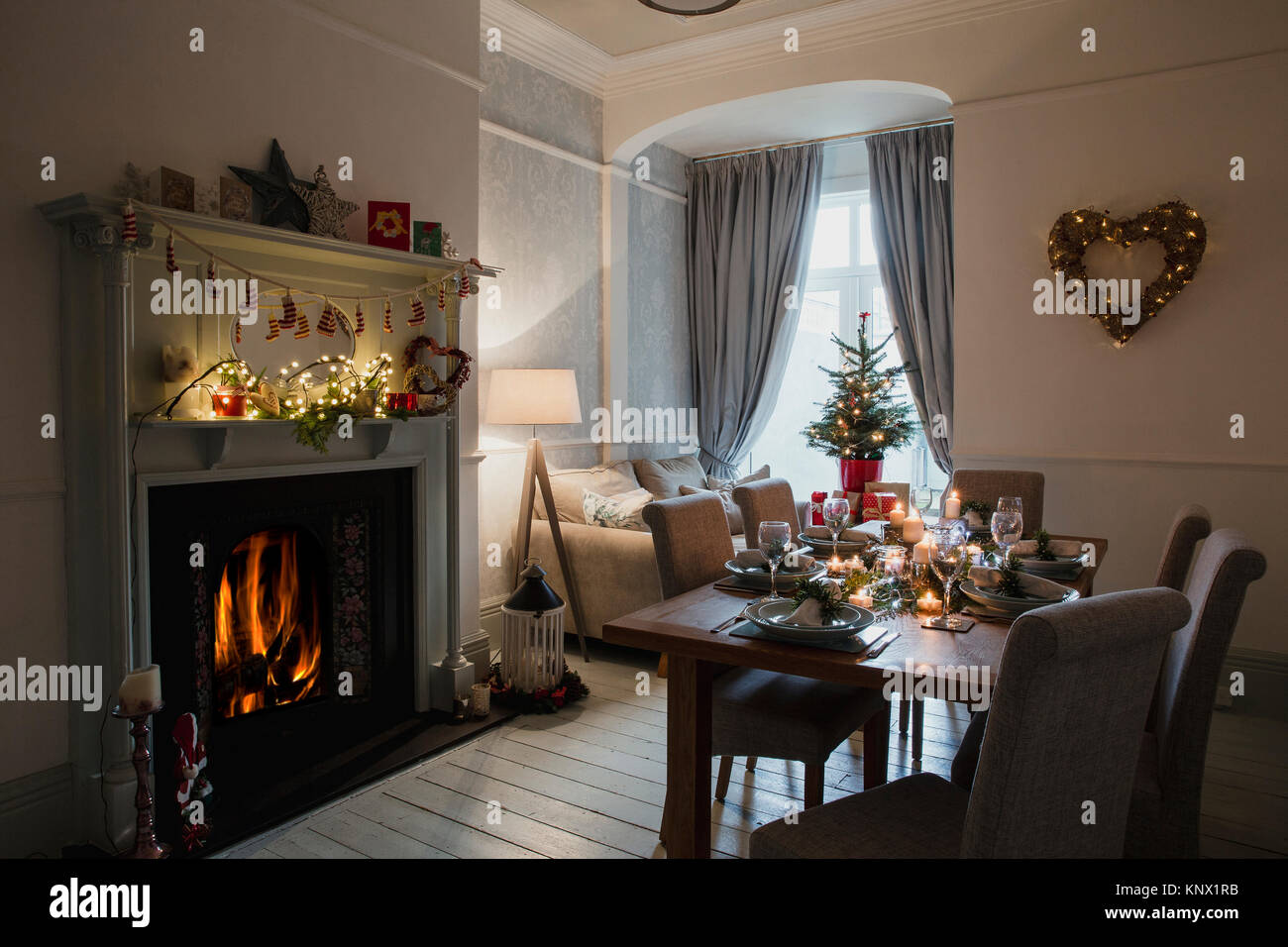 Sala da pranzo di casa decorato per il Natale. La tabella viene impostato su Pronto per la cena di Natale e il fuoco e le candele accese. Foto Stock