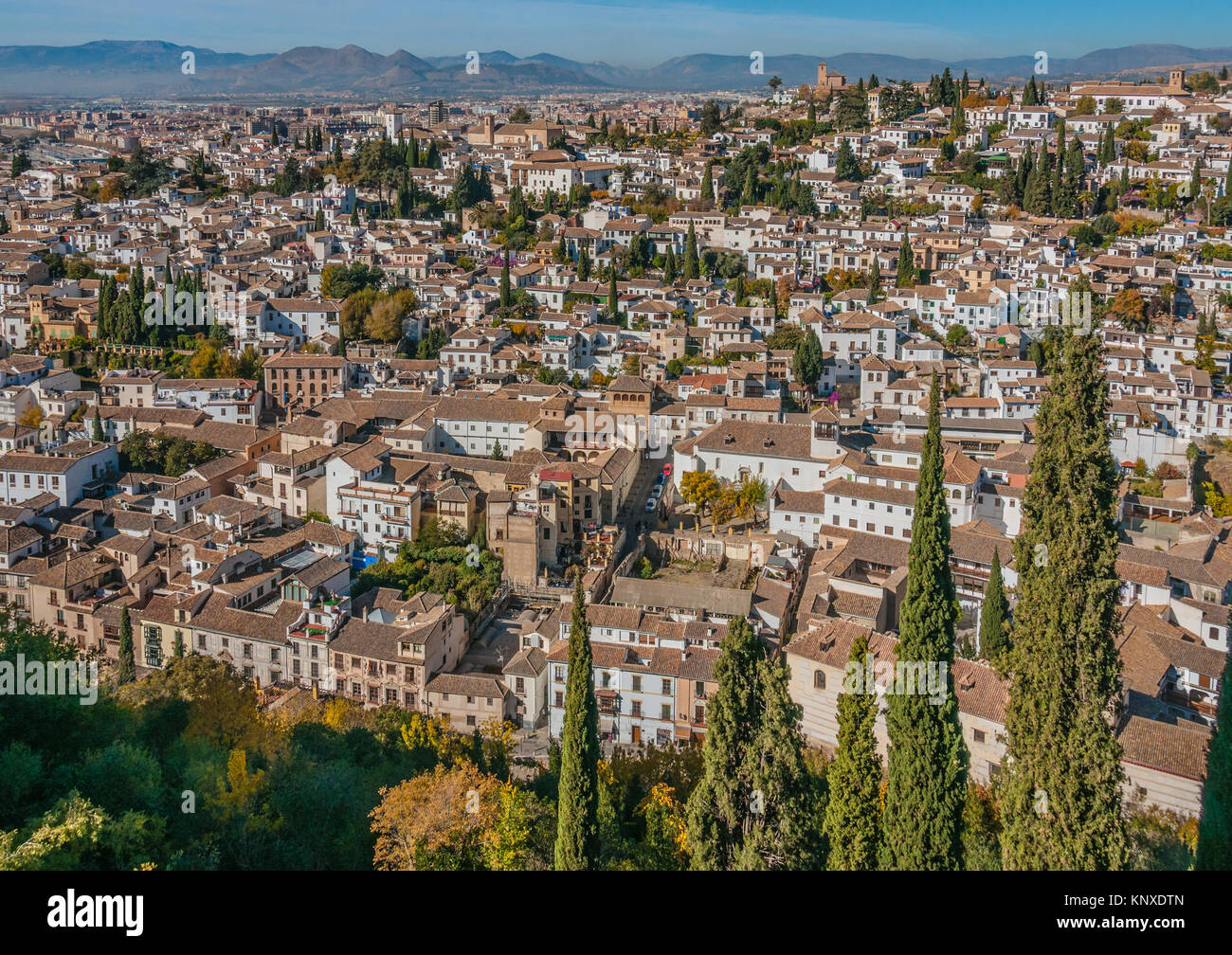 Vista la vecchia parte di moresco di Granada. Case bianco marrone con tetti di tegole, marrone chiese, il verde dei cipressi e Misty Mountains sotto il cielo blu Foto Stock