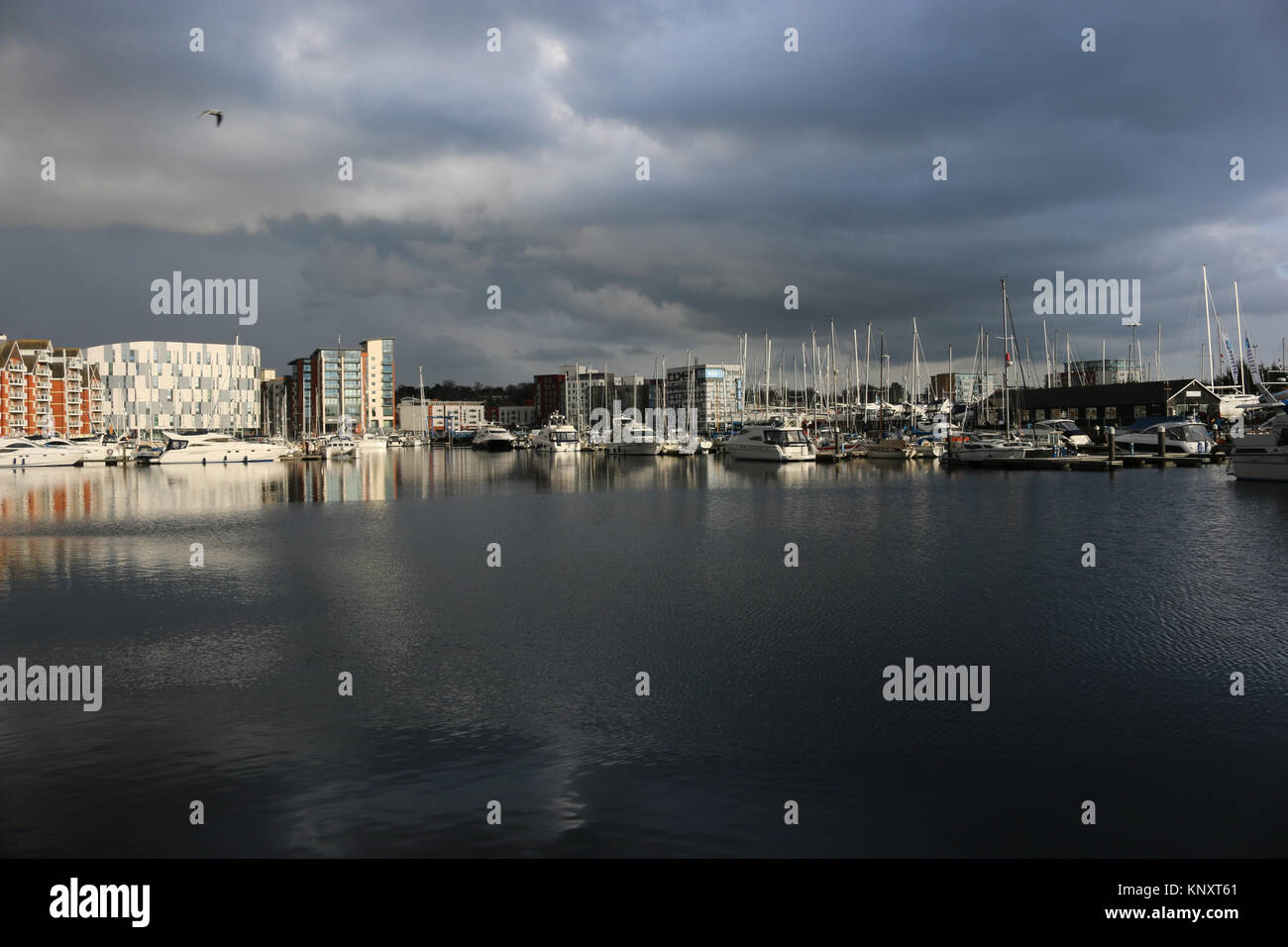 Porto turistico sul lungomare di Ipswich e edifici circostanti con nuvole tempeste molto scure e luce solare che illuminano le barche e gli edifici Foto Stock