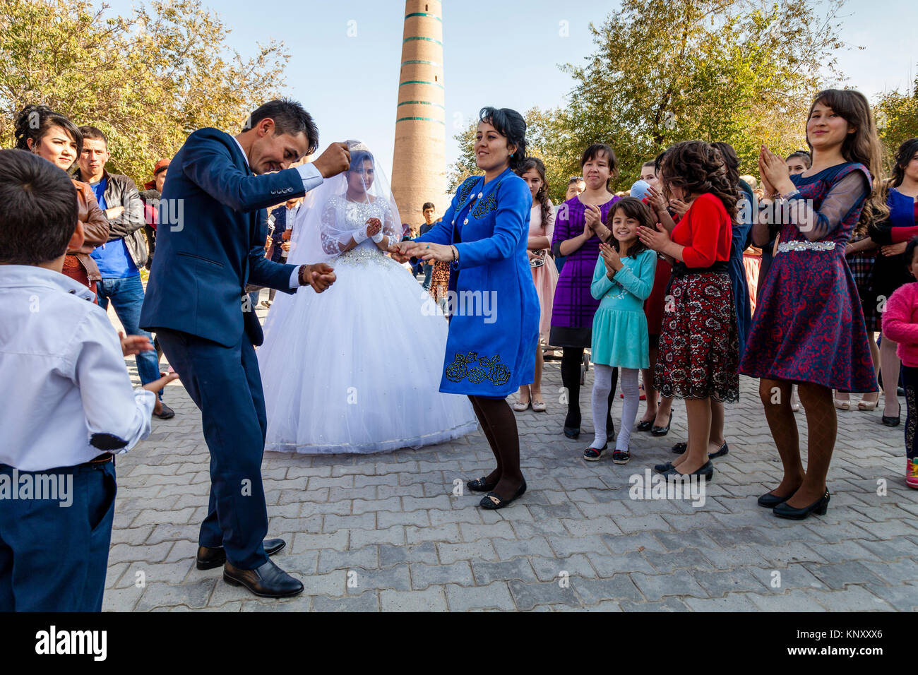 Gli ospiti dei matrimoni in ballo la strada durante una festa di nozze, Khiva, Uzbekistan Foto Stock