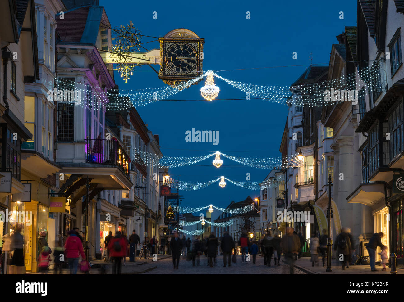 La High Street in Guildford con luci di Natale e la famosa Guildhall orologio in oro in blu ora su una notte tarda giornata di shopping, England Regno Unito Foto Stock