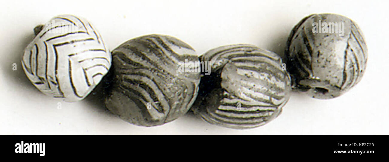 Quattro perle di vetro colorate del periodo antico, che illustrano l'artigianato decorativo in ornamenti personali. Foto Stock