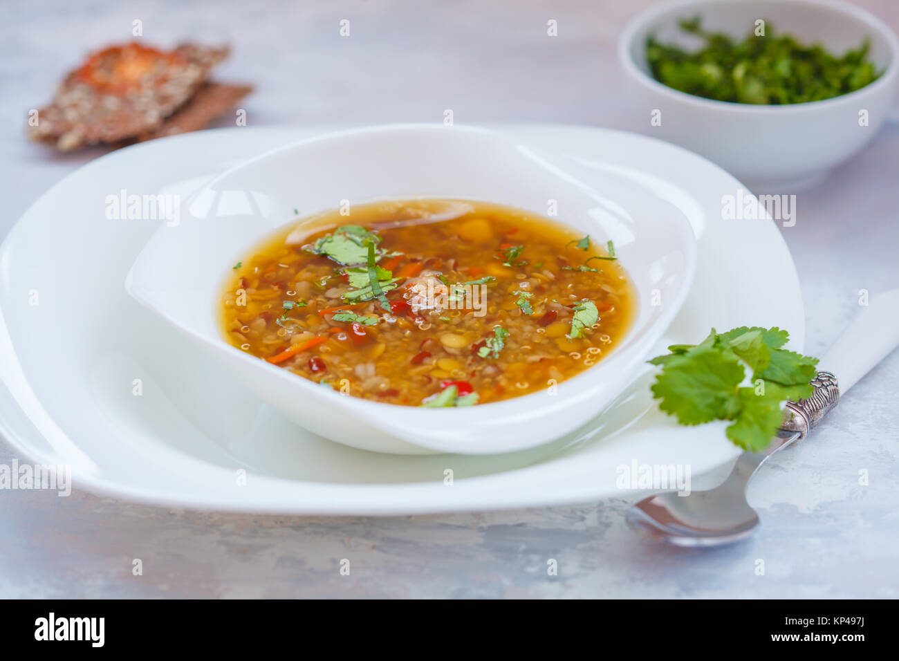 Peruviano zuppa di quinoa, rosso di riso e lenticchie in una piastra bianca con erbe e fette biscottate. Sano cibo vegan concetto. Foto Stock