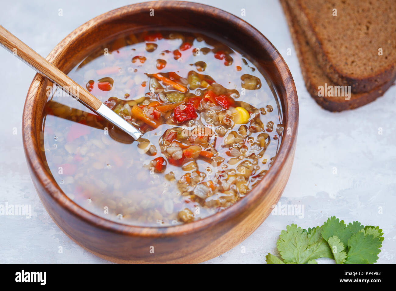 Zuppa peruviana con la quinoa, rosso di riso e lenticchie in una ciotola di legno con erbe e pane di segale. Sano cibo vegan concetto. Foto Stock