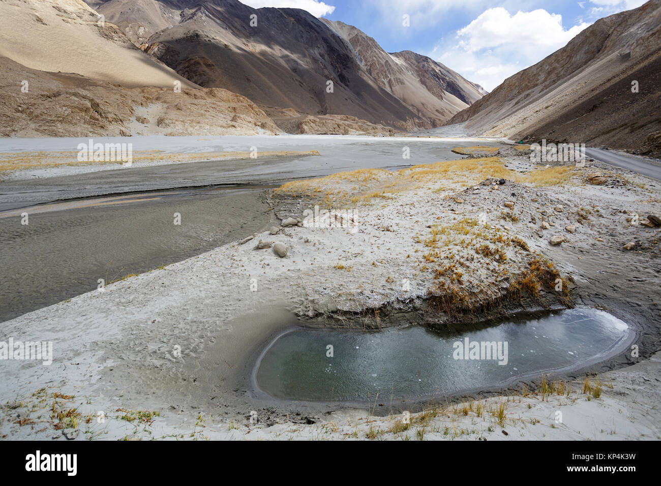 Strada di montagna che conduce da Chang La pass per Pangong Tso con fori per l'acqua e gli allevamenti di yak al pascolo nei retro, Ladakh, Jammu e Kashmir in India. Foto Stock