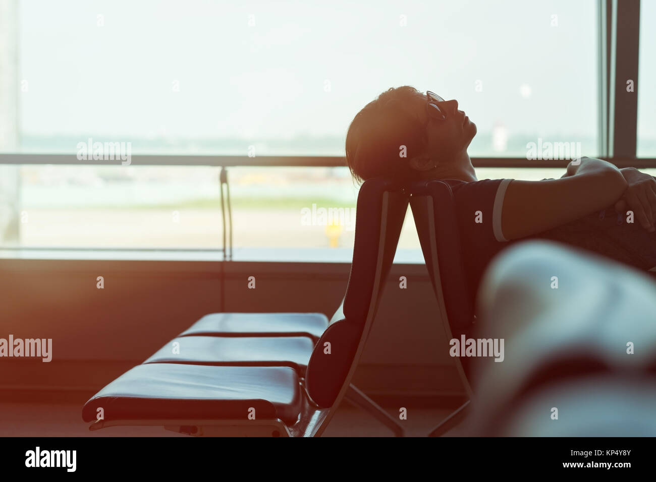 Stanco caucasian donna che dorme nella sala di attesa di un aeroporto in attesa del volo Foto Stock