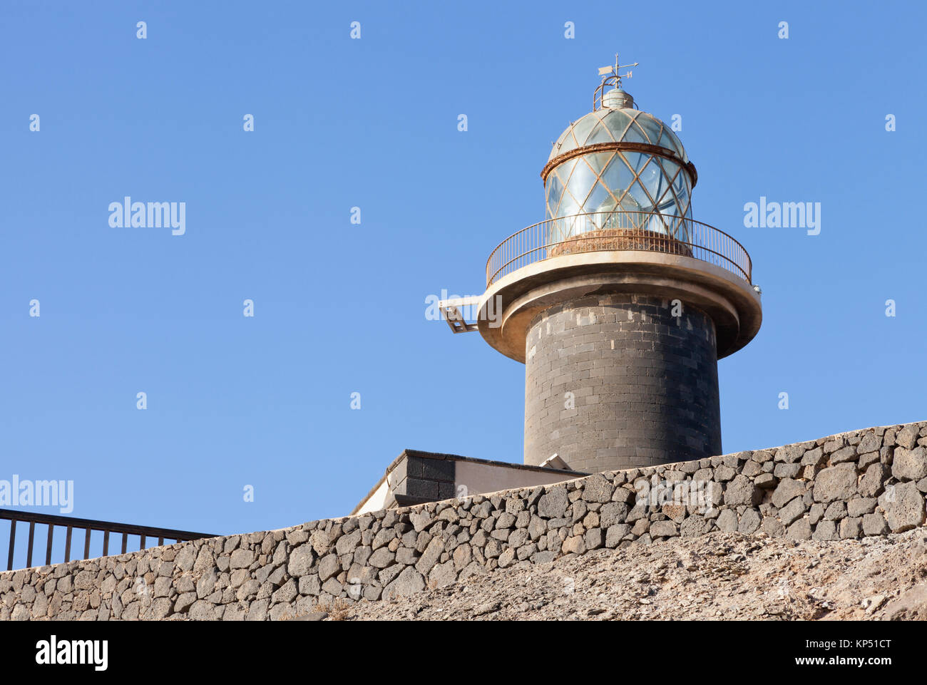 Costiera di torre faro con vetro nell'alloggiamento superiore, sul muro di pietra . Foto Stock