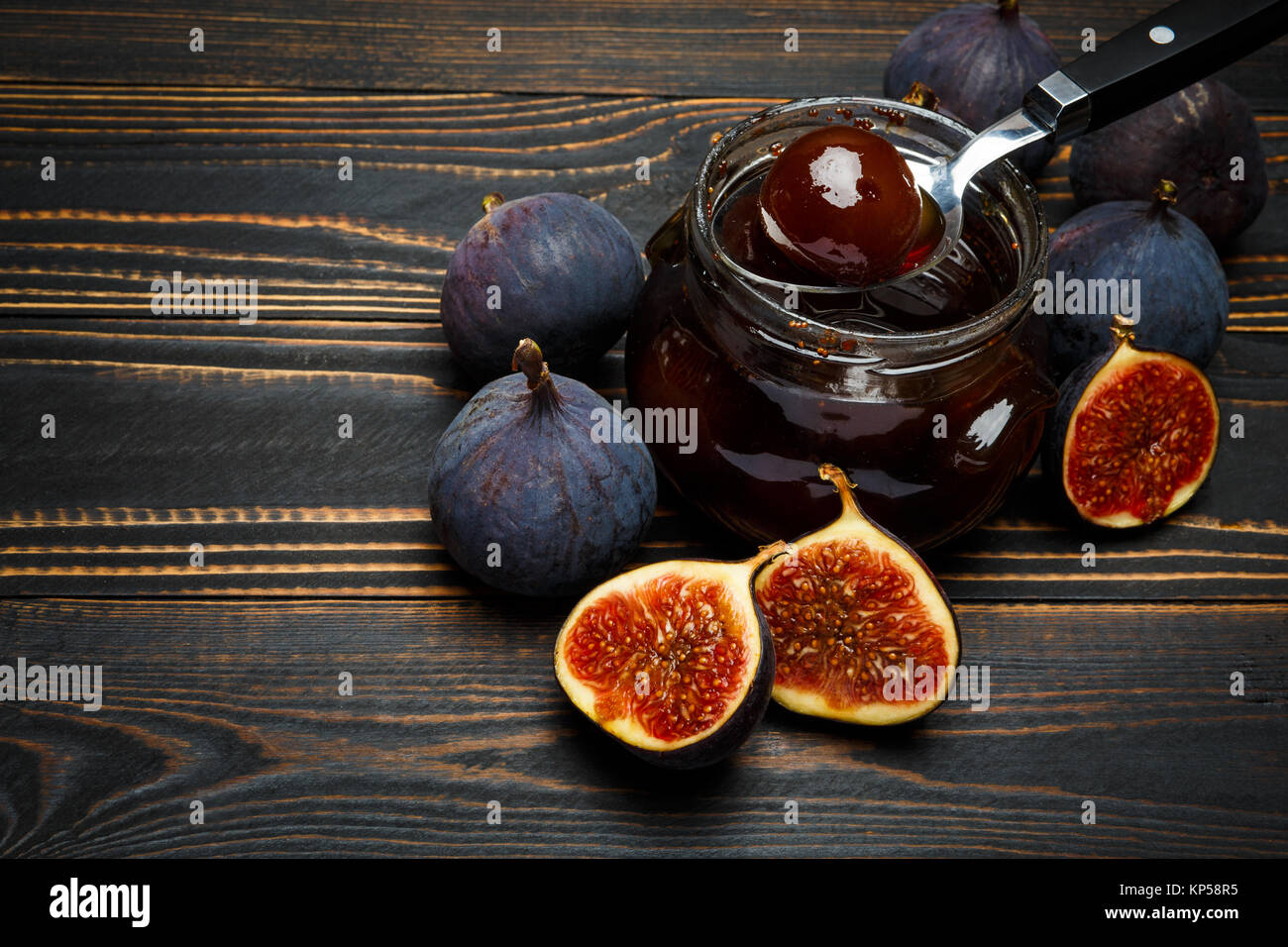 Vasi di vetro pieno di confettura di fichi e fig frutti al buio su un sfondo di legno Foto Stock