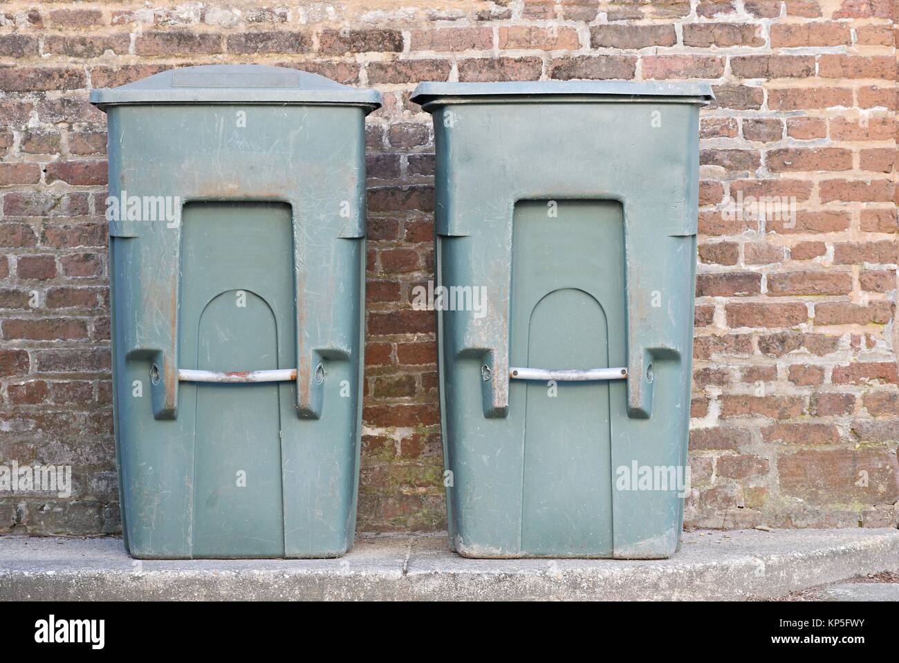 Due vecchi verde scomparti di cestino accanto a un vecchio rosso muro di mattoni Foto Stock