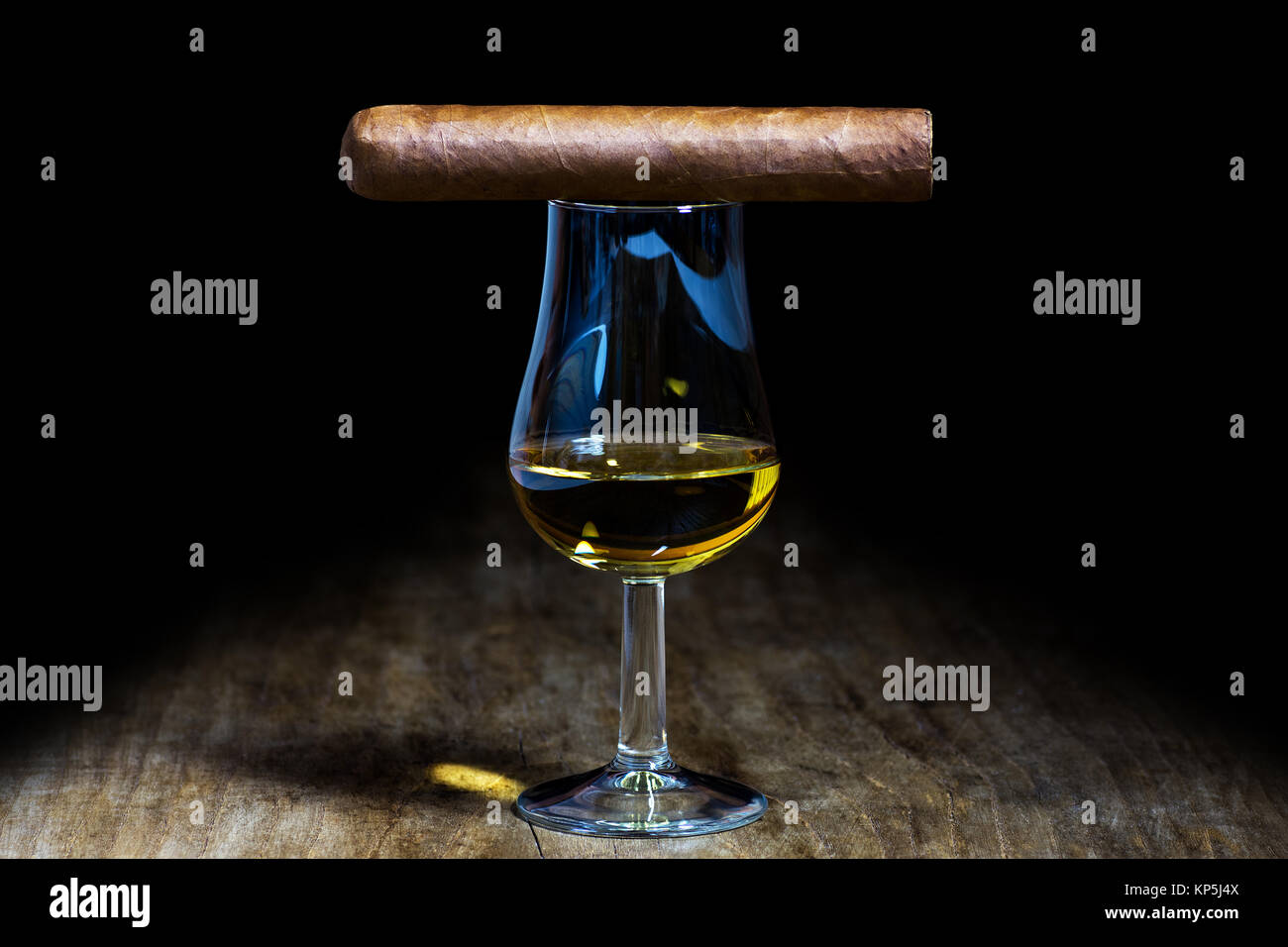 Un bicchiere di whiskey con un sigaro in piedi su un vecchio tavolo in legno Foto Stock