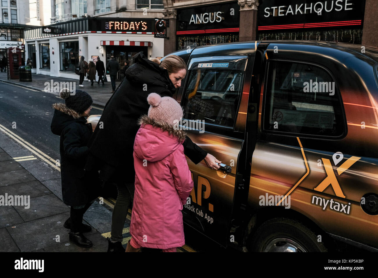 Donna con bambini salutando un taxi a Londra, Regno Unito Foto Stock