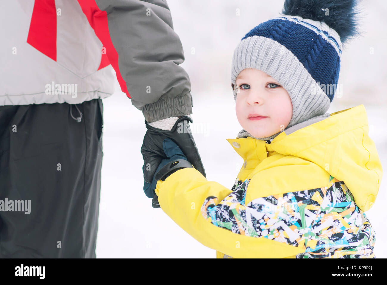 Padre trattiene il ragazzo in mano in abbigliamento invernale, inverno, famiglia, mano nella mano, lo stile di vita Foto Stock