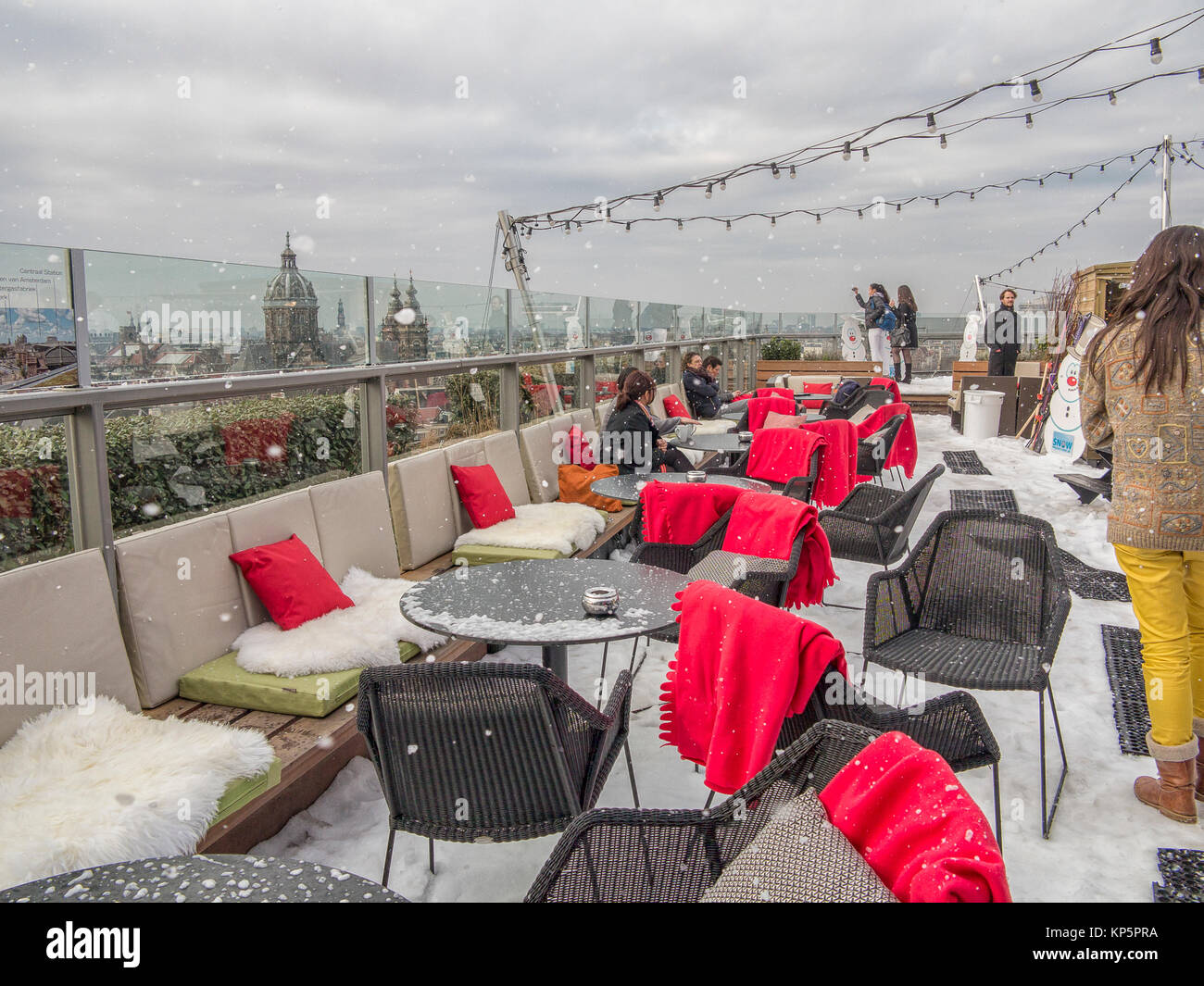 Persone in un ristorante sul tetto di Amsterdam nella neve con una vista del centro storico della cittã . Foto Stock