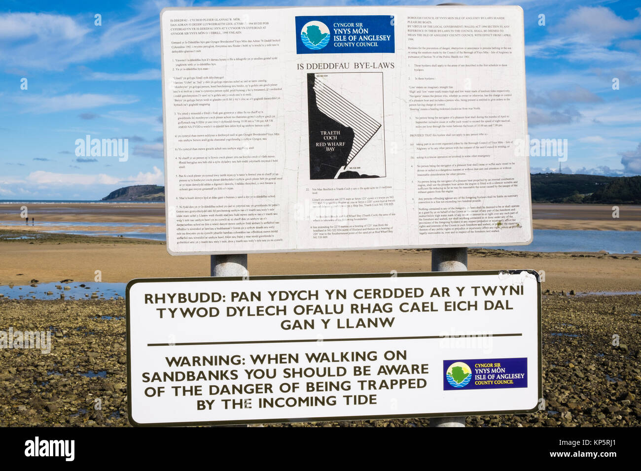 Bilingue segno di avvertimento circa il pericolo di essere tagliati fuori dalla marea con Ynys Mon consiglio bye-leggi. Red Wharf Bay (Traeth Coch) Isola di Anglesey nel Galles REGNO UNITO Foto Stock