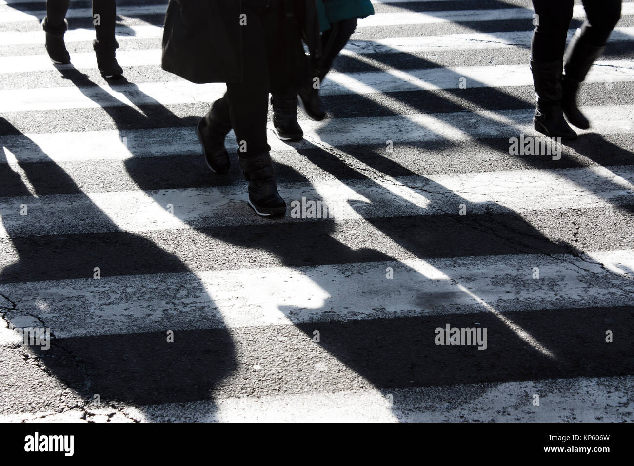 Ombre e sagome di persone che attraversano la strada di città in inverno in bianco e nero Foto Stock