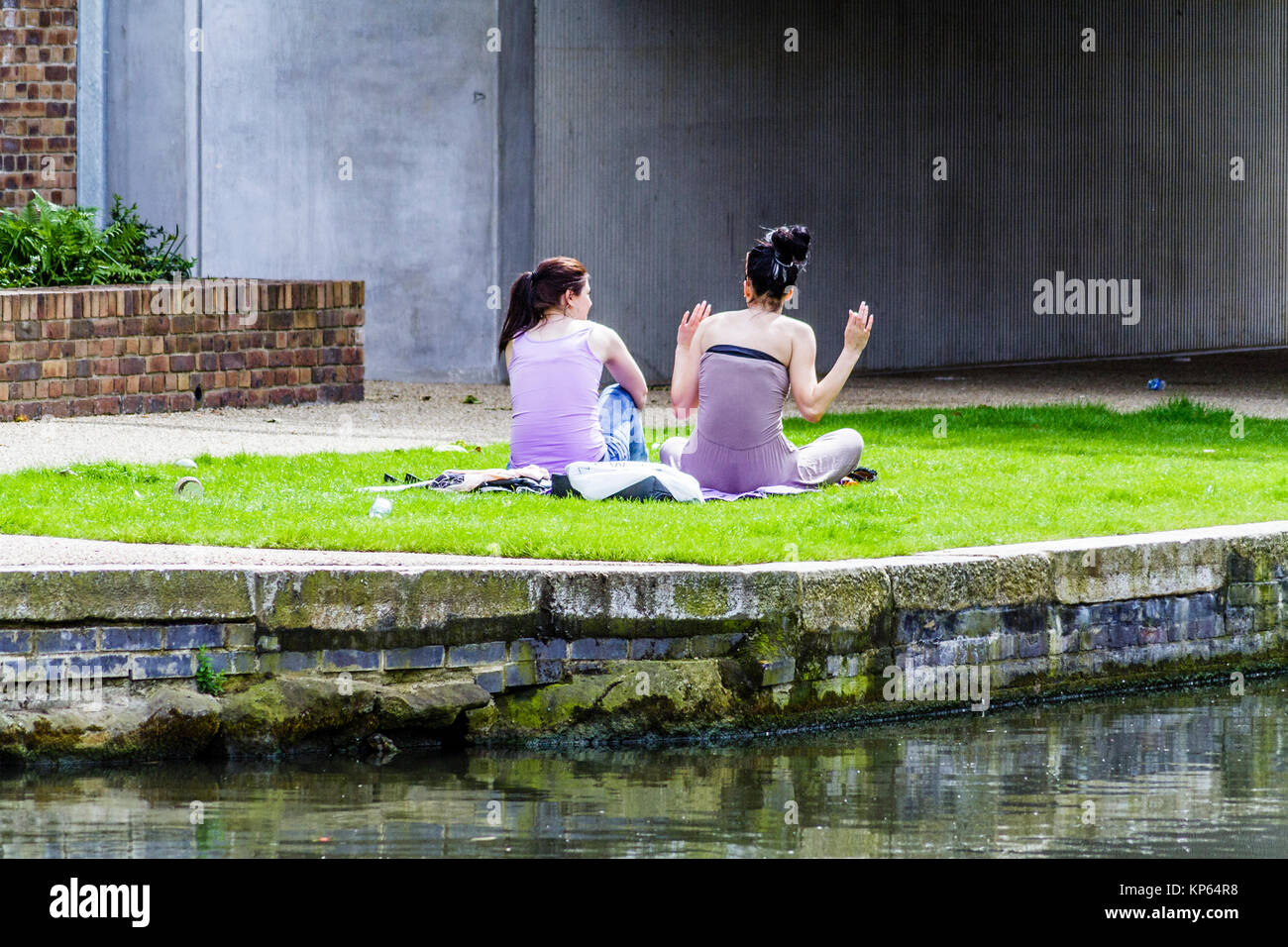 Due giovani donne godendo il sole da Regent's Canal a Kings Cross, London, Regno Unito Foto Stock