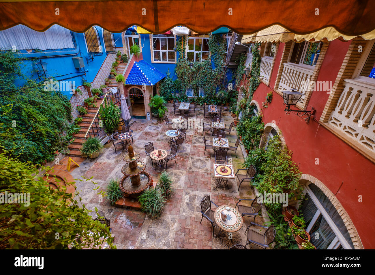 Colorata terrazza che si affaccia sul cortile interno ricco di decorazioni e pareti ricoperte con piante Foto Stock