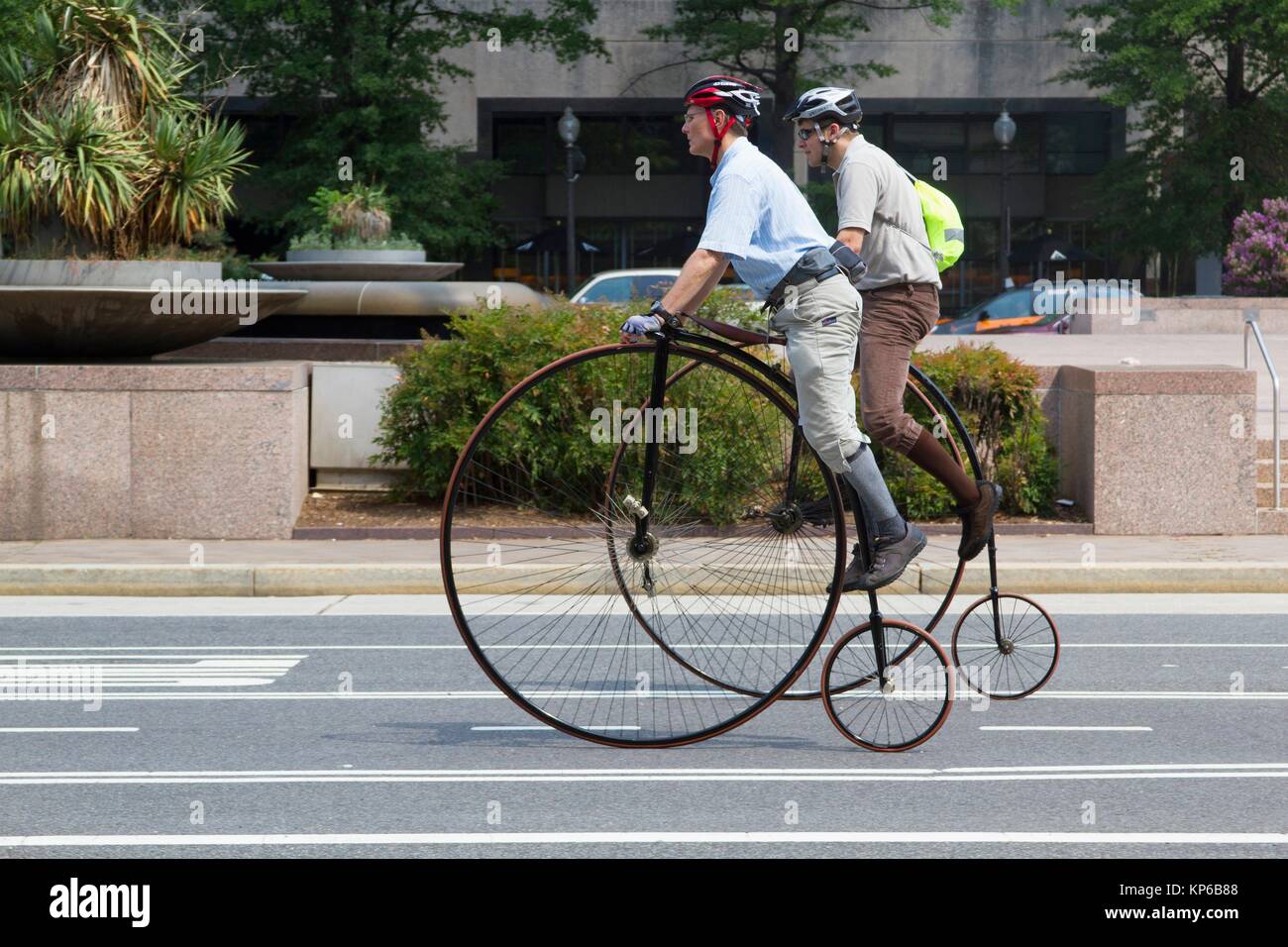 Due maschi caucasici ride in vecchio stile di biciclette con molto grandi  ruote e ruote piccole. Essi stanno cavalcando Penny Farthing' bike. Il  montaggio mettendo un Foto stock - Alamy