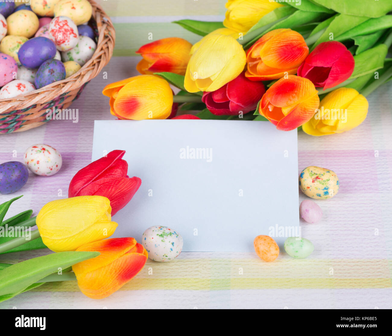 Tulipani colorati e Pasqua candy attorno ad una busta vuota Foto Stock
