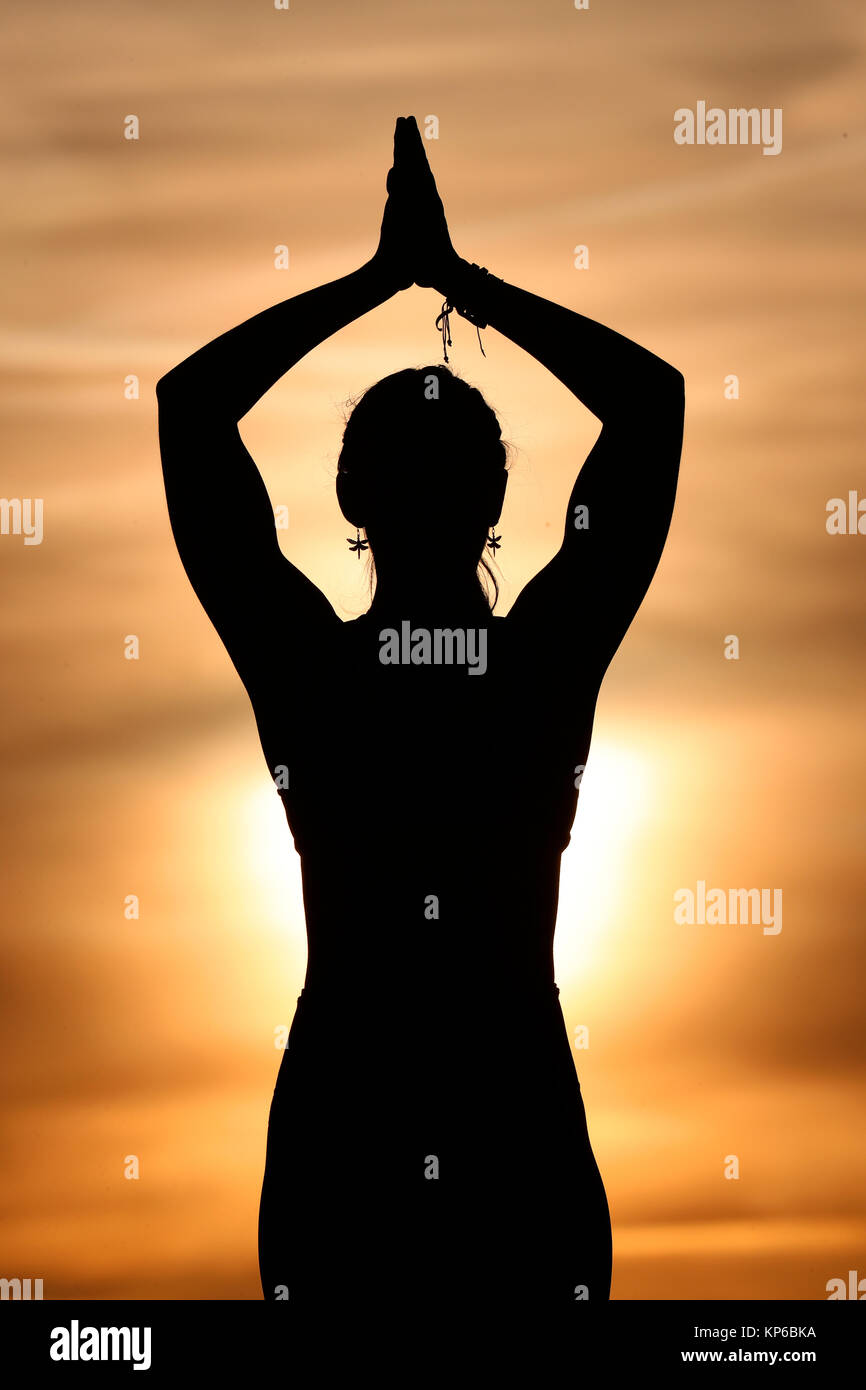 Silhouette di donna a praticare yoga contro la luce del sole di sera. Tadasana : la posizione della montagna. Sulle Alpi francesi. La Francia. Foto Stock