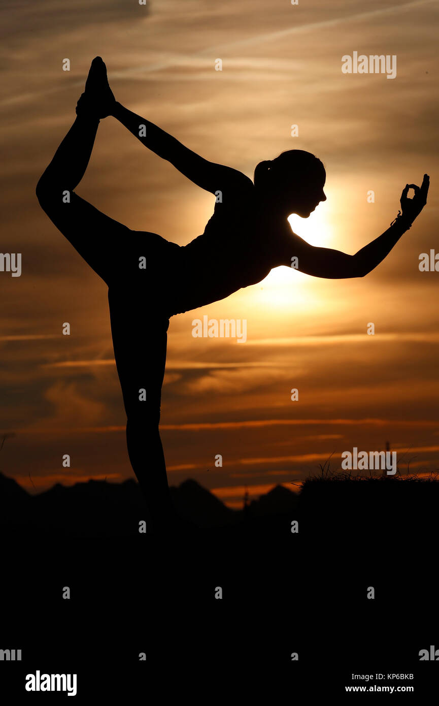 Silhouette di donna a praticare yoga contro la luce del sole di sera. Natarajasana: Signore della danza. Sulle Alpi francesi. La Francia. Foto Stock