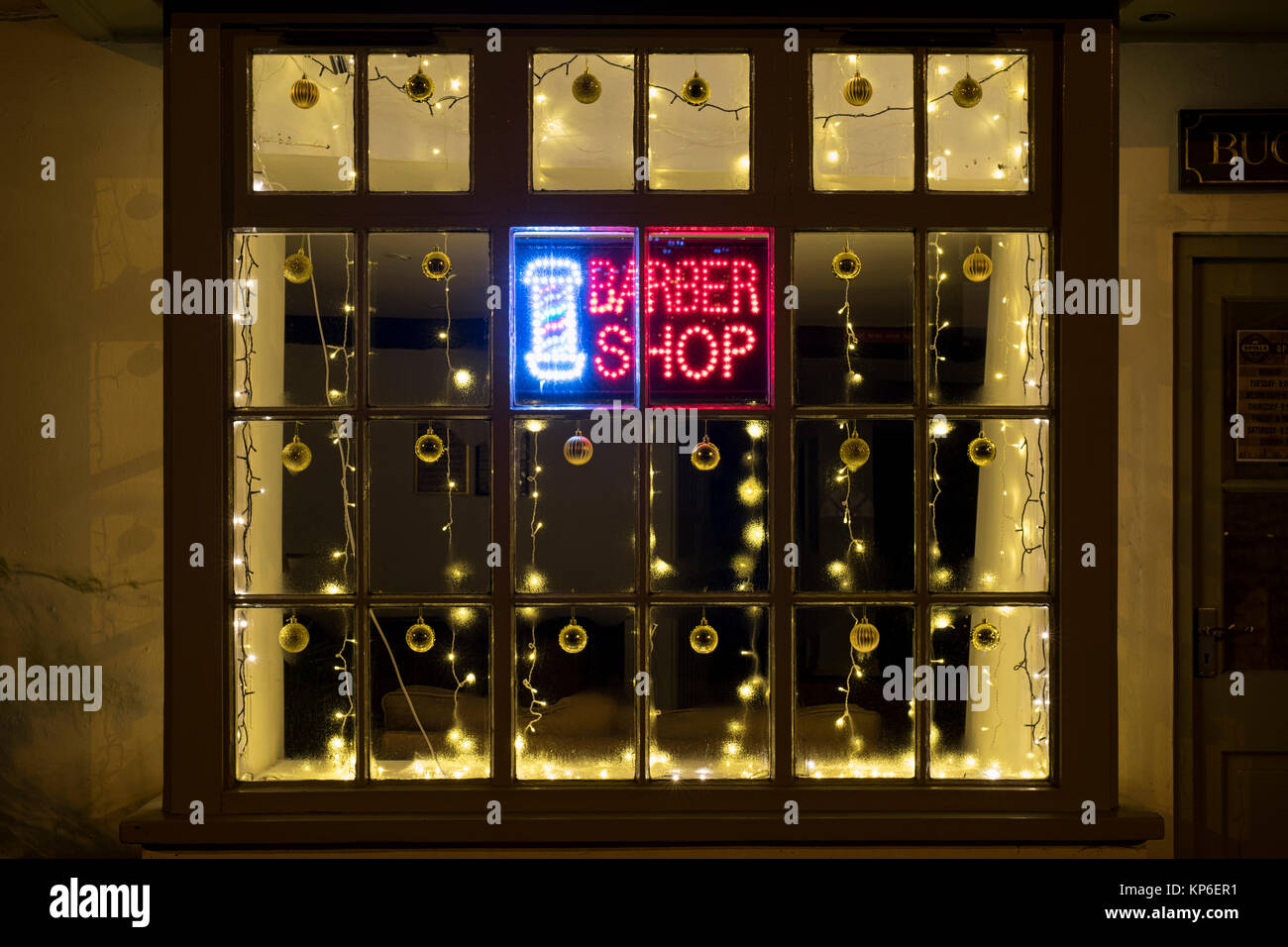 Le decorazioni di Natale e il LED di firmare in un negozio di barbiere finestra. Chipping Norton, Cotswolds, Oxfordshire, Inghilterra Foto Stock