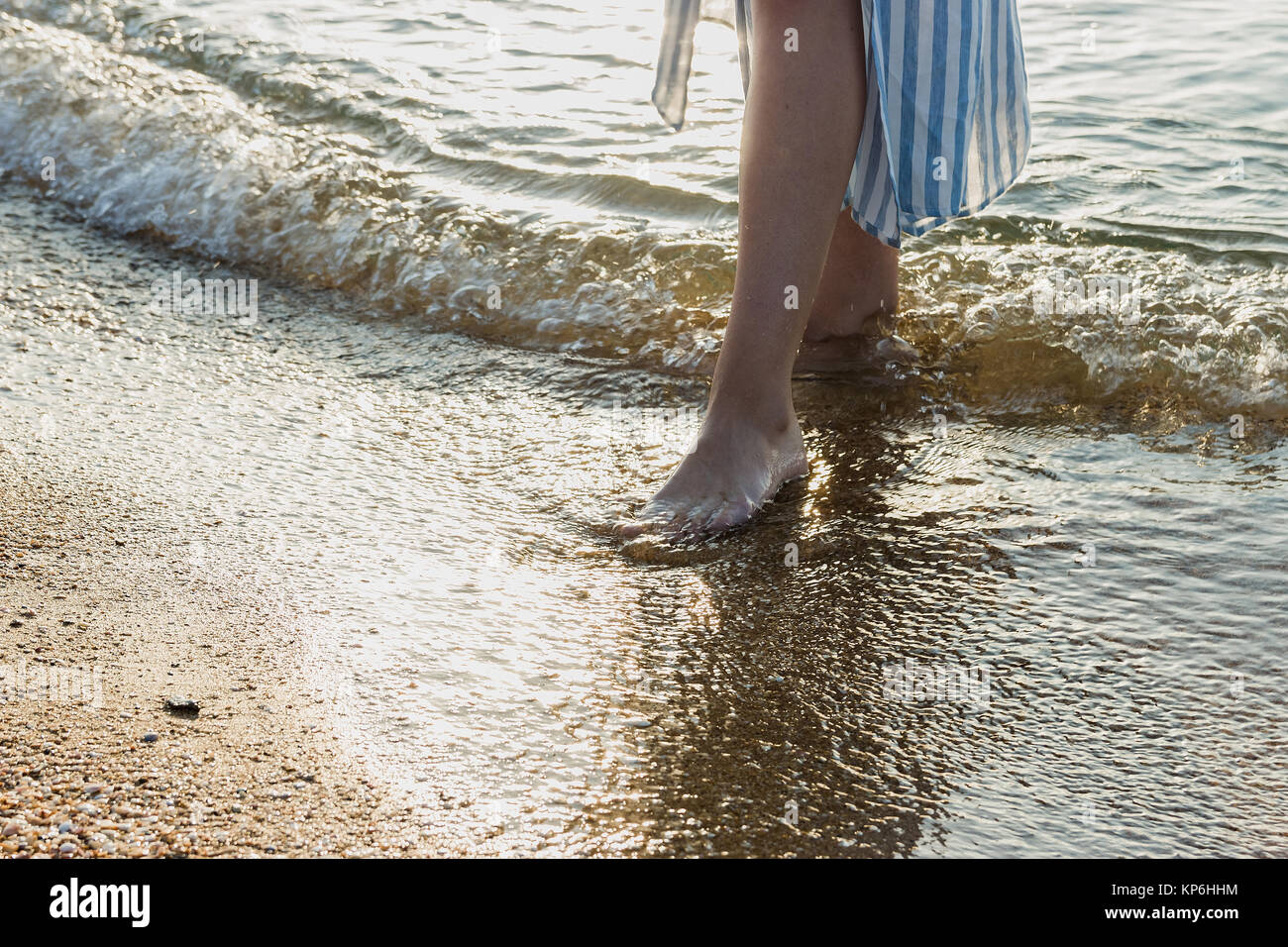 Donna in piedi scalzi toccato dal dolce mare onde da surf sulla spiaggia di sabbia Foto Stock