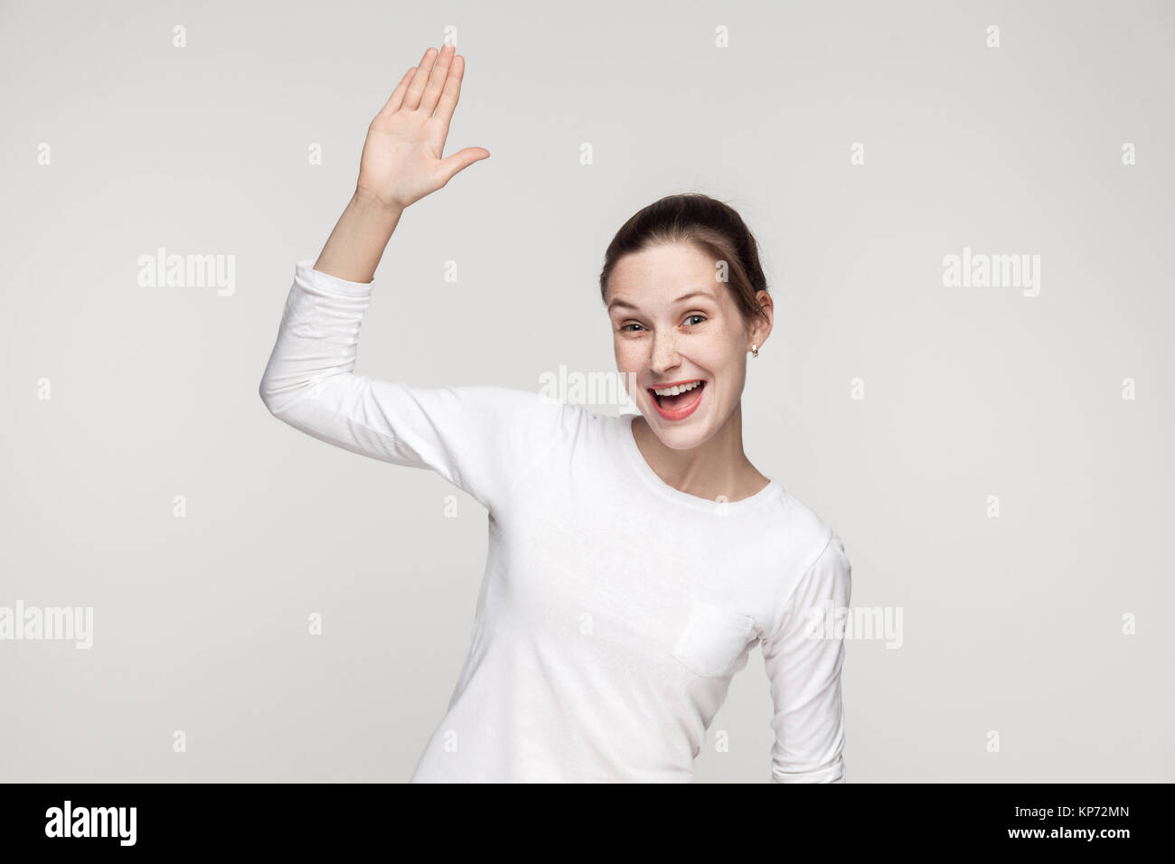 Ciao! Come stai? La felicità della donna che mostra ciao segno. Studio shot, sfondo grigio Foto Stock