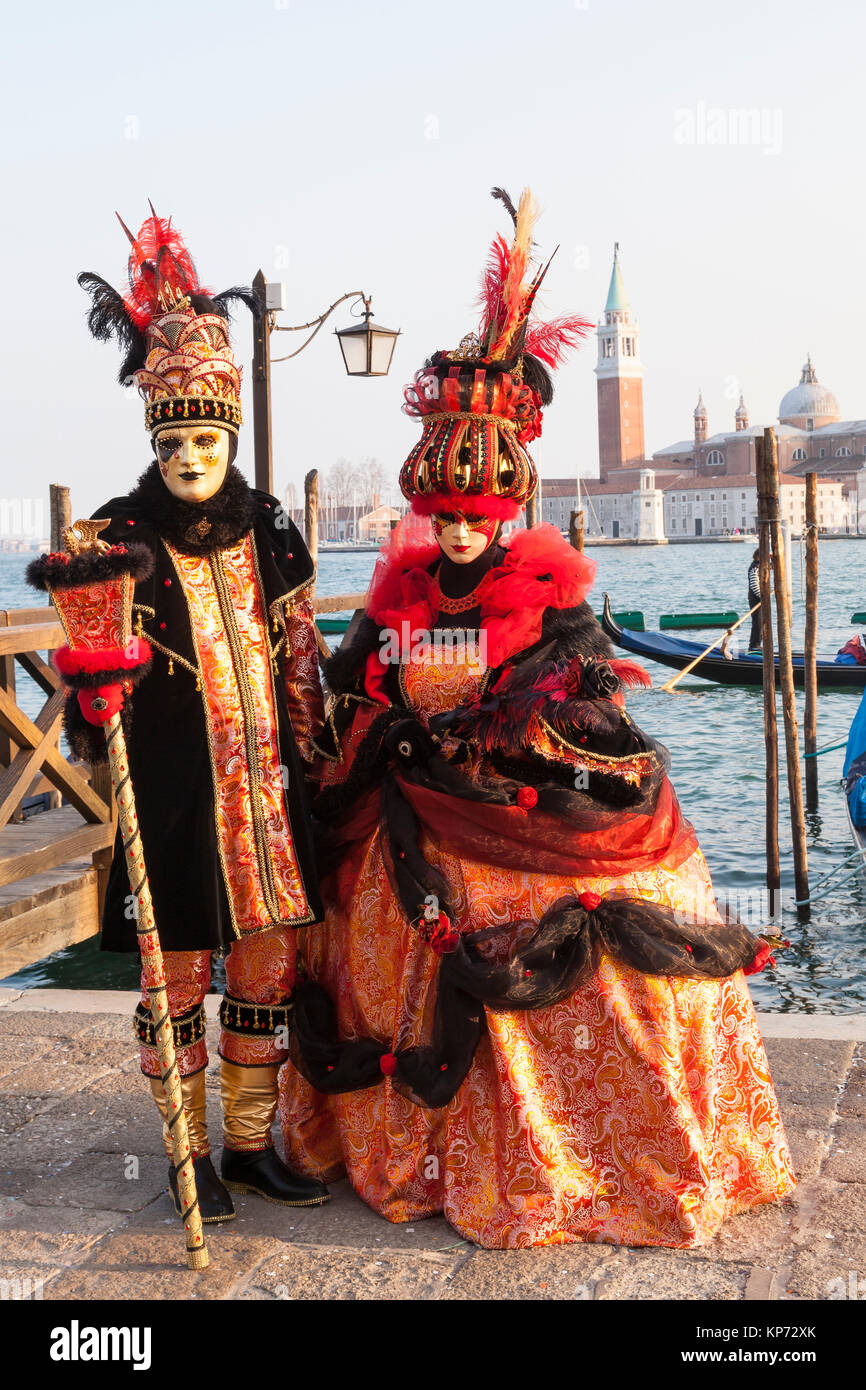 Il Carnevale di Venezia, Venezia, Veneto, Italia, giovane nel classico  costume arancione in posa presso la laguna al tramonto Foto stock - Alamy