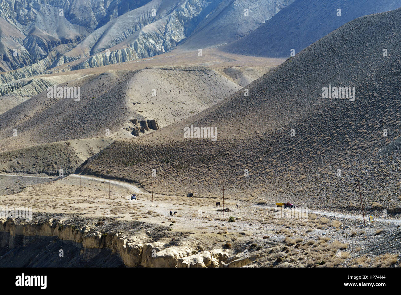 Strada sterrata seguendo il Kali Gandaki valley tra Kagbeni e Tangbe, Mustang superiore, Nepal.Trekkers, trattori e cavaliere visibile in distanza. Foto Stock