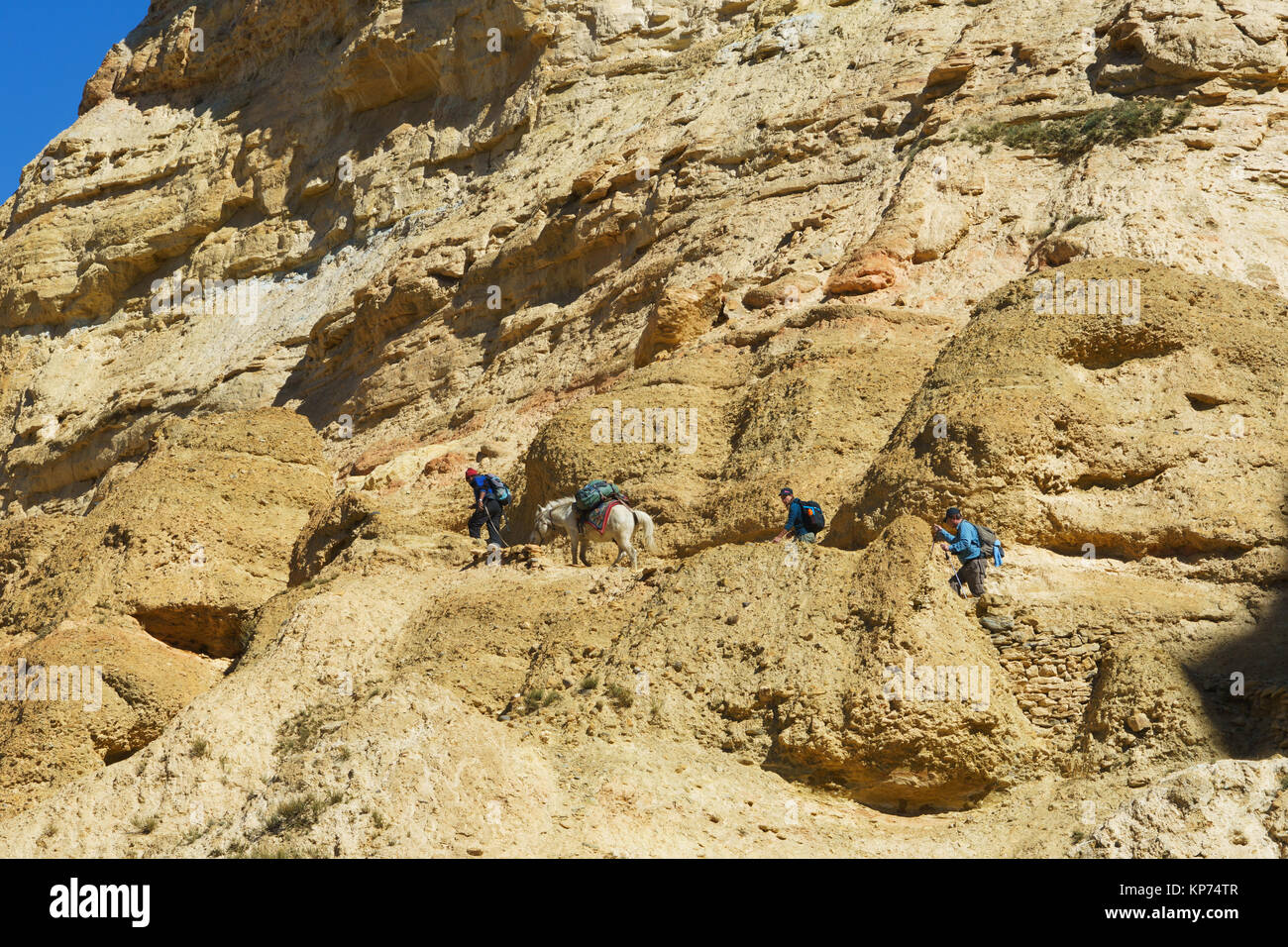 Due escursionisti e un cavaliere sul sentiero sulla scogliera tra chele e Samar, Mustang Superiore regione, Nepal. Foto Stock