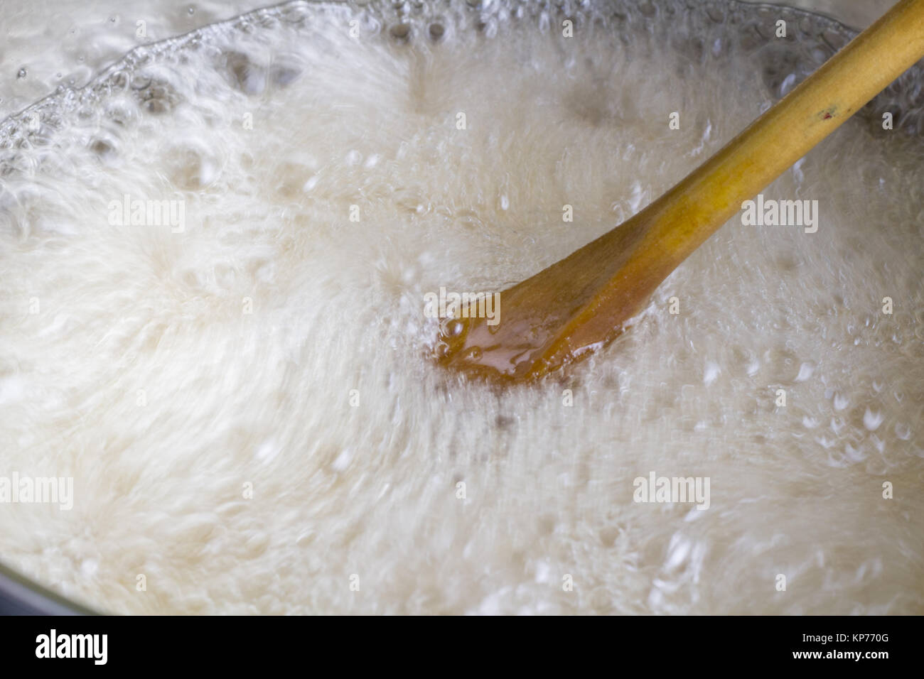 Il cucchiaio di legno mescolando rapidamente il liquido in ebollizione vicino fino in pentola di cottura - Fractal texture di movimento Foto Stock