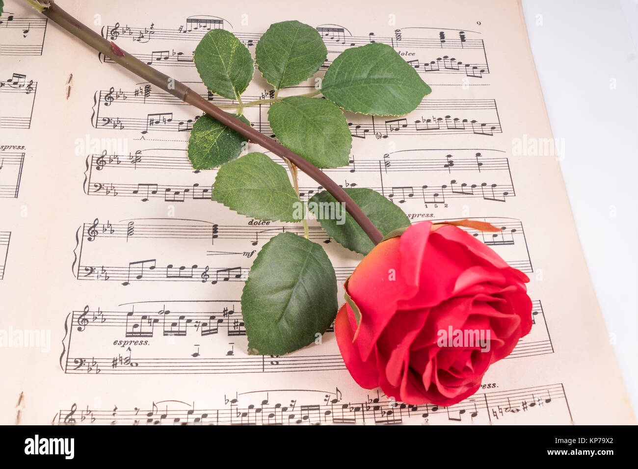 Una rosa rossa su una vecchia partitura musicale Foto stock - Alamy