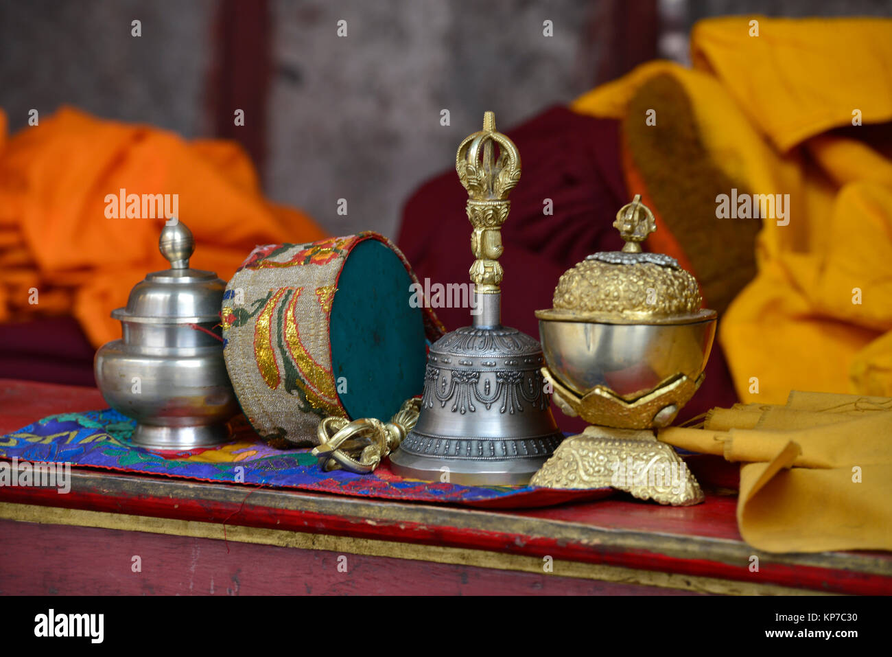 Rituale di oggetti buddista per la puja: una campana tibetana, un tamburo e ciotole d'argento sulla preghiera tabella di una lama. Foto Stock
