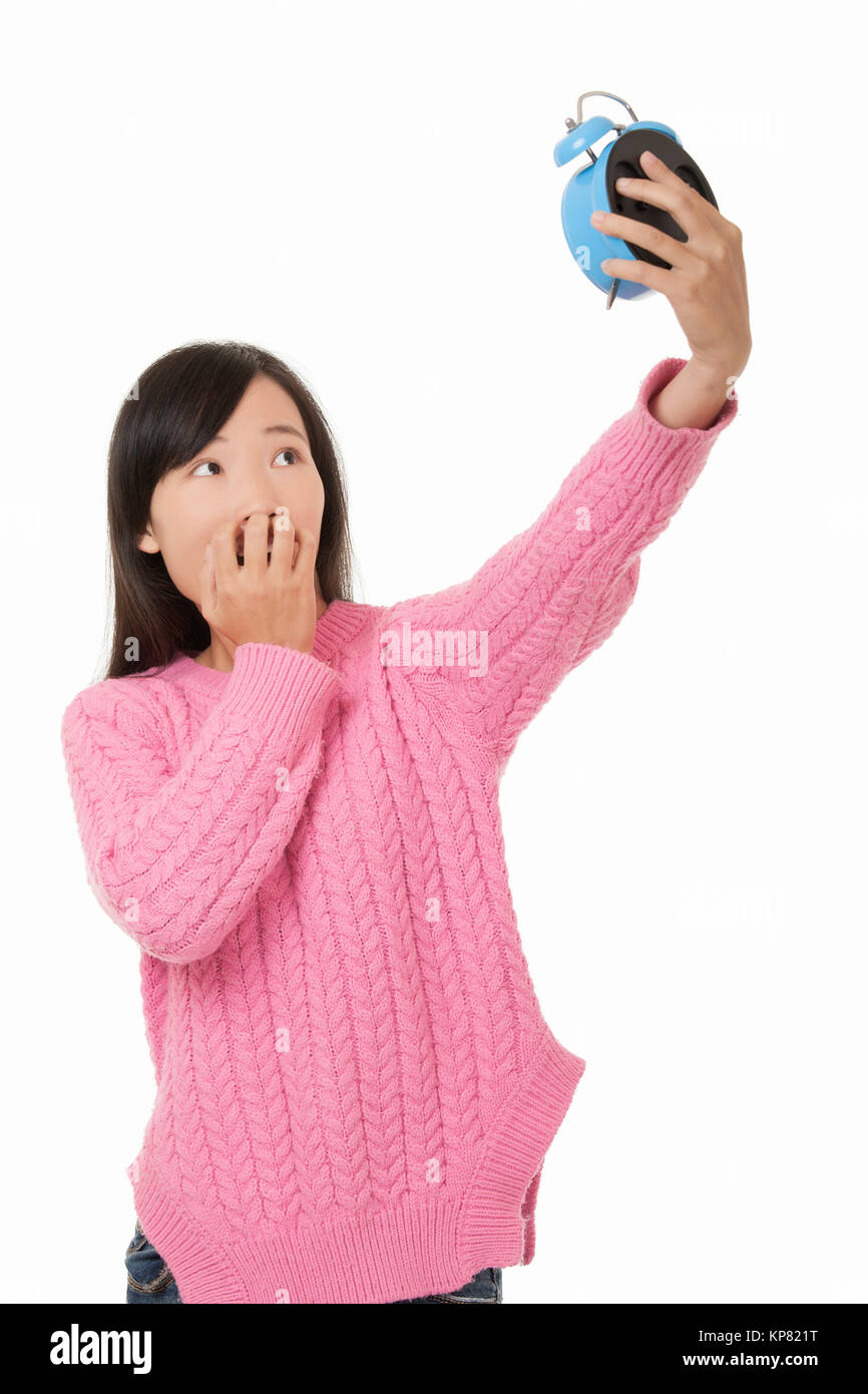 Bella donna cinese tenendo un blu sveglia e cercando surpresed isolato su uno sfondo bianco Foto Stock