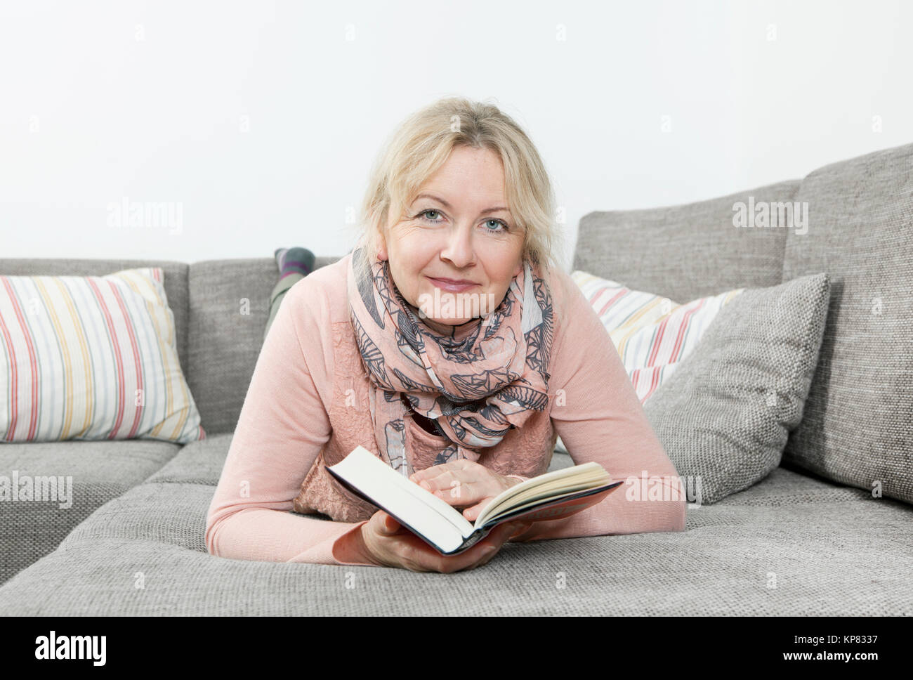 Donna che legge un libro sul divano Foto Stock