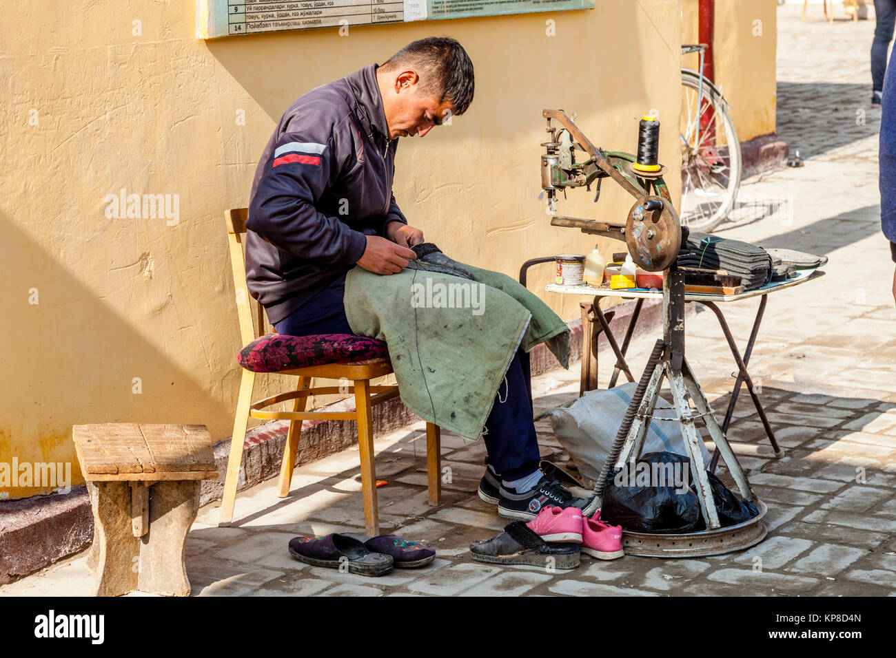 Un calzolaio operanti nel mercato, Khiva, Uzbekistan Foto Stock