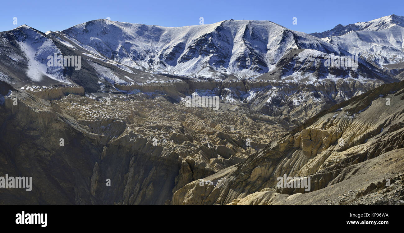 Inverno in montagna: gamme della montagna sono coperti di neve sulle cime, qui di seguito sono di colore giallo e marrone rocce, l'Himalaya. Foto Stock