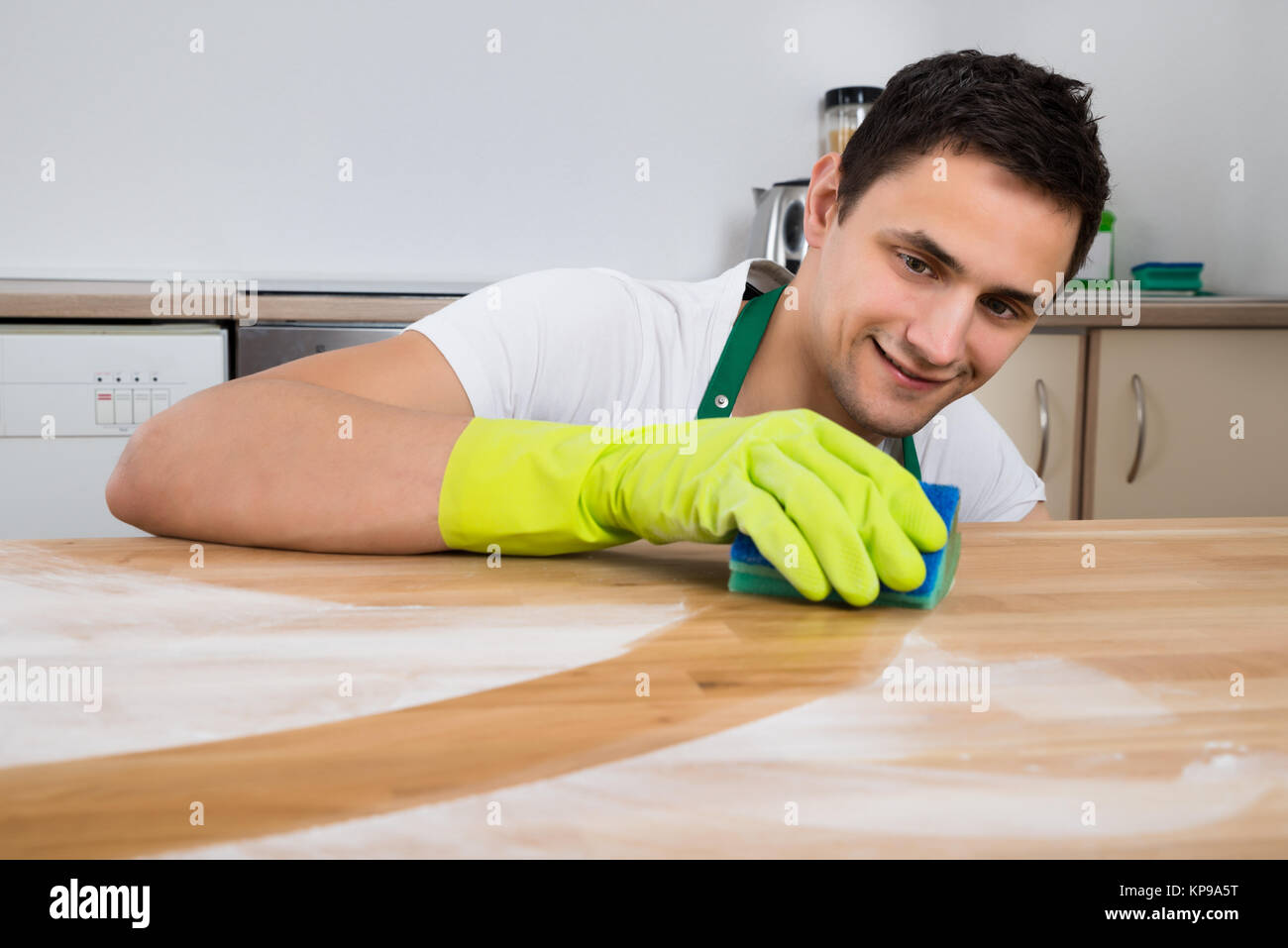 L'uomo la pulizia della polvere sul tavolo di legno con spugna Foto stock -  Alamy