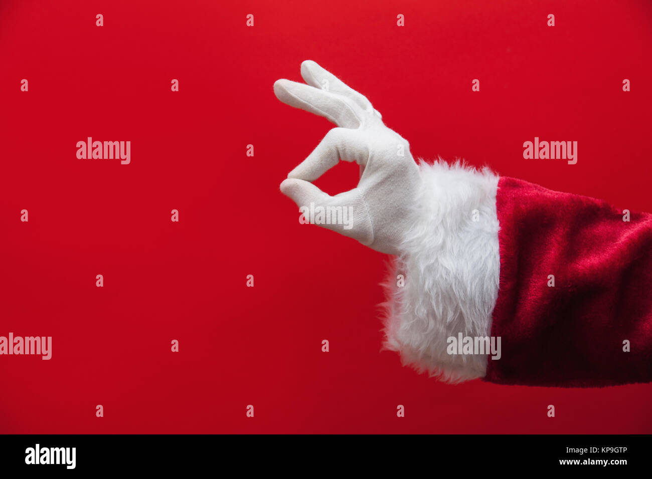 Santa Claus mano okay gesto contro uno sfondo rosso Foto Stock