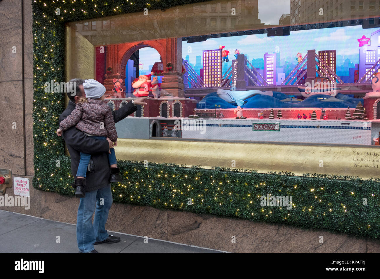 Un anonimo grandfatherather mostra il suo nipote a Macy's finestra di Natale in Piazza Herlad a Manhattan, New York City. Foto Stock
