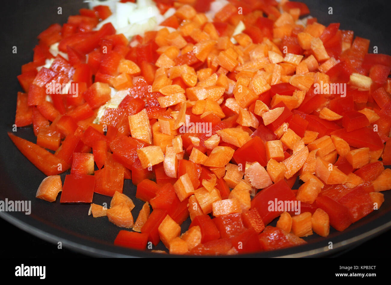 Fresco a dadini di peperoni rossi, le carote e le cipolle in un non stick skillet pronto per la frittura Foto Stock