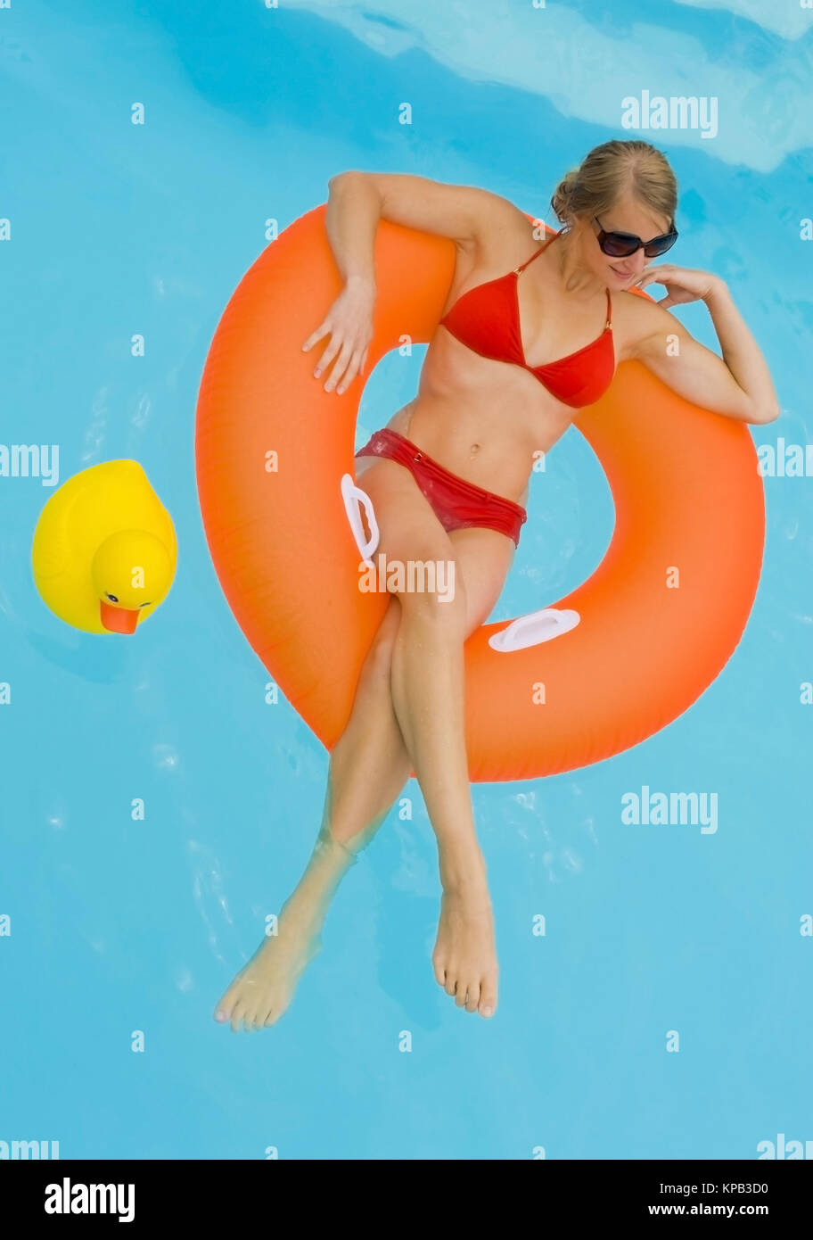 Modello di rilascio, Junge Frau im Bikini entspannt im Schwimmreifen im Pool - giovane donna con pneumatici flottanti in piscina Foto Stock