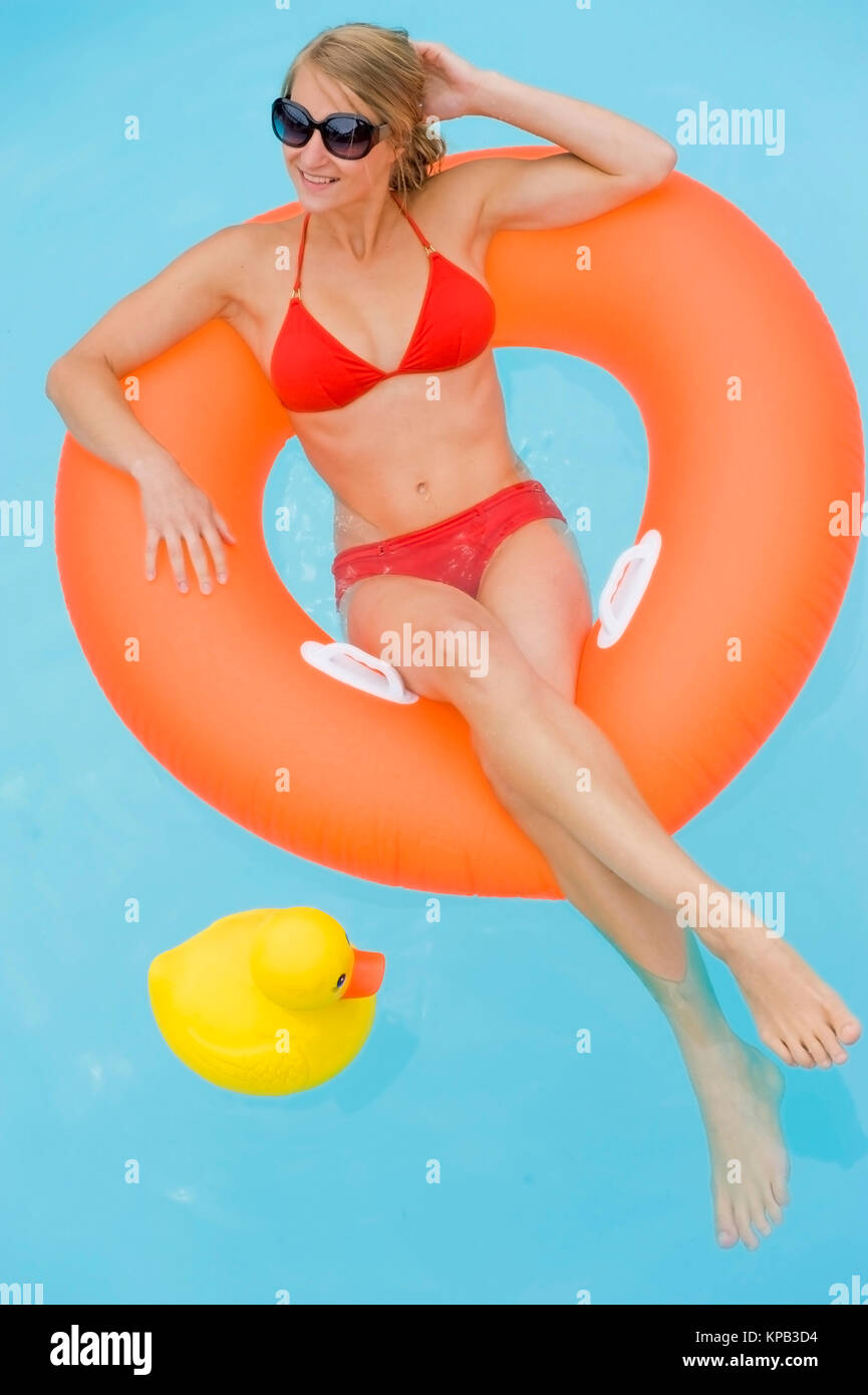 Modello di rilascio, Junge Frau im Bikini entspannt im Schwimmreifen im Pool - giovane donna con pneumatici flottanti in piscina Foto Stock