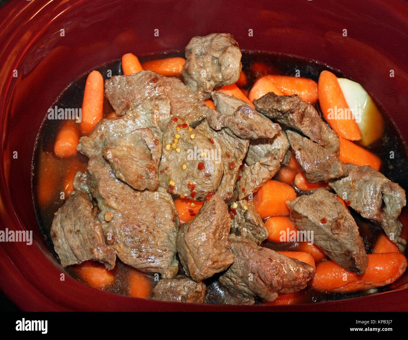 Strati di fettine di patate bianche, pelati mini baby carote e rosolato cottura carni bovine in uno slow cooker Foto Stock